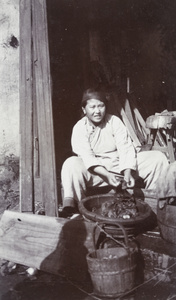 A woman washing laundry in the doorway of a carpenter's workshop