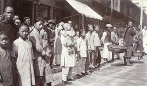 Children and adults standing and watching at the side of a street, Shanghai