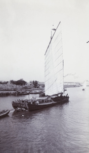 A trading junk with sail towing a smaller boat