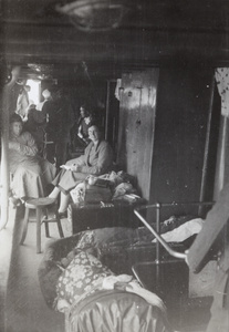 Ethel Vinden sitting on her camp cot on a boat, in Luzhou region