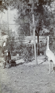 Gigi Detring in the Commissioner's garden, Tientsin, with a crane