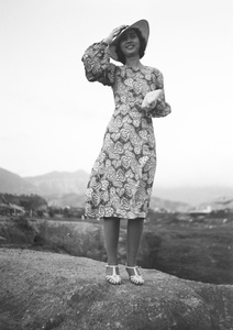 Bea Hutchinson holding on to her hat while modelling a paisley print dress, near the Army Sports Ground, Mongkok, Hong Kong