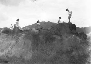 Kristine and Patricia Thoresen, Jim Hutchinson, and Olav Kulstad playing on a rocky outcrop, near the Army Sports Ground, Mongkok, Hong Kong