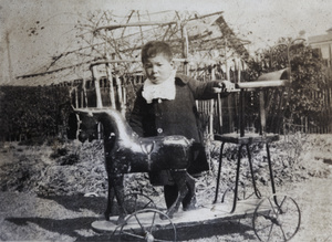 Fred Hutchinson standing with a wooden horse and chair on a wheeled platform, 35 Tongshan Road, Hongkou, Shanghai