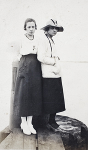 Two women standing on a wooden water pylon, near Shanghai