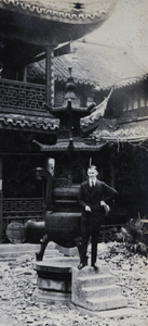 Young man standing on steps to a censer in a temple in the Chinese city, Shanghai