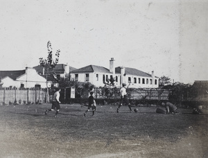 Gardener weeding a lawn during a game of soccer, Shanghai