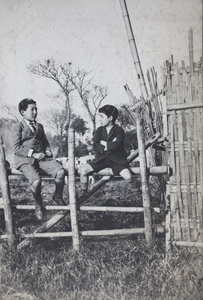 Dick and Fred Hutchinson sitting on top of a paddock fence, Hongkou, Shanghai