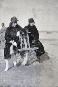 Two young women sitting on a wheelbarrow, Wusong, February 1920