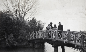 Charles Hutchinson standing with three young women on a wooden bridge, Hongkou Park, Shanghai