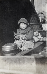 Boat-dwelling child wearing a crochet hat on a river boat, Shanghai