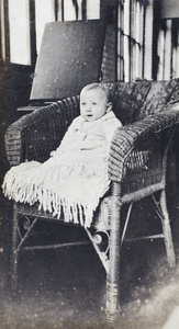 Baby wrapped in a blanket and sitting in a wicker chair, Shanghai