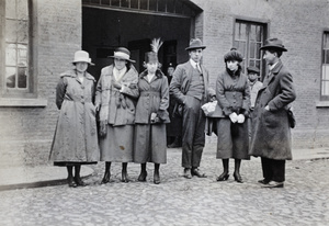 Bill and Tom Hutchinson standing in a cobbled street with four young women, Shanghai