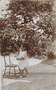 Bea Hutchinson standing outdoors by a wooden chair, Moganshan