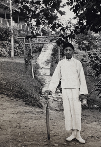 A man with a parasol standing in front of steps leading to a summer house, Moganshan