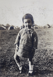 Bea Hutchinson wearing a hand knitted jumper, standing in a park with canvas tents, Shanghai 