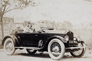Mrs Hansen posing behind the wheel of an automobile, with Baba and a uniformed driver in the back seat, Dalney Road, Hongkou, Shanghai