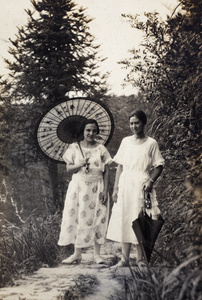 Margie and Sarah Hutchinson with parasols, pausing on a hill path, Moganshan