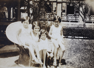 Gladys, Mabel, Lorrie, and Bea Hutchinson sitting together on a large rattan chair by the garden summer house, 35 Tonghan Road, Hongkou, Shanghai