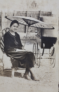 Sarah Hutchinson sitting beside a baby pram in the garden, 35 Tongshan Road, Hongkou, Shanghai