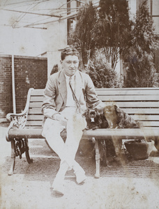 Mr Carrington on a garden bench, with two Pekingese dogs, Shanghai
