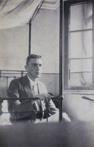 George Danson sitting on an iron-frame bed, 35 Tongshan Road, Hongkou, Shanghai