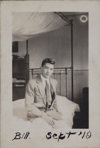 Bill Hutchinson sitting on an iron-frame bed, 35 Tongshan Road, Hongkou, Shanghai