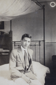 Bill Hutchinson sitting on an iron-frame bed, 35 Tongshan Road, Hongkou, Shanghai 