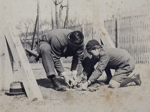 Charles and Dick Hutchinson bandaging the paw of a dog in the garden, 35 Tongshan Road, Hongkou, Shanghai