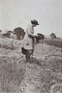 Sarah Hutchinson holding camera and whip in a field near Tongshan Road, Hongkou, Shanghai