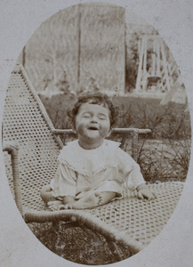 Koskey baby sitting up and laughing on a rattan garden lounger, 35 Tongshan Road, Hongkou, Shanghai