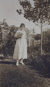 Hannah holding an illustrated newspaper standing in the garden, 35 Tongshan Road, Hongkou, Shanghai