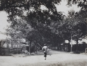 Agricultural worker walking along Tongshan Road carrying a long-handled hoe, Hongkou, Shanghai