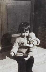 Bea Hutchinson holding a doll and sitting on the verandah steps, 35 Tongshan Road, Hongkou, Shanghai