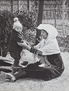 Sonny Hutchinson standing on a wooden stool while supported by Sarah Hutchinson, in the garden of 35 Tongshan Road, Hongkou, Shanghai