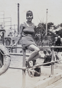Mabel Parker sitting on a metal railing at the Open Air Pool, Hongkou, Shanghai, 1924