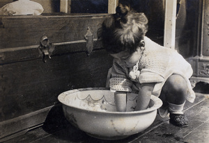 Bea Hutchinson with her hands in a wash basin on the floor, 35 Tongshan Road, Hongkou, Shanghai
