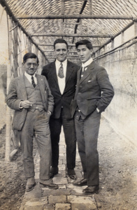 Unidentified man, Thomas Kirby and Tom Hutchinson standing under a garden trellis, 35 Tongshan Road, Hongkou, Shanghai