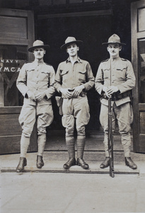 Mr Farnham, Bill Hutchinson and 'Doc' Houghton, American Company Shanghai Volunteer Corps members, standing outside the entrance to the Navy YMCA, Shanghai