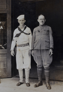 American Navy sailor and American Company Shanghai Volunteer Corps officer standing at the entrance to the Navy YMCA, Shanghai, 1925
