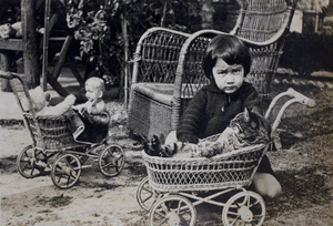 Bea Hutchinson with a cat in a play pram, in the garden of 35 Tongshan Road, Hongkou, Shanghai