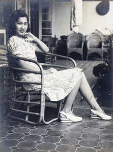 Bea Hutchinson sitting in a bent-cane chair on the veranda of the apartment block 166-188 Prince Edward Road, Kowloon, Hong Kong