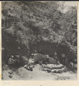 Guides, donkeys, and villagers resting in the shade beside a well on the way to the Lost Tribe country.