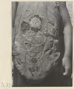 Child wearing an apron with appliquéd figure in the Lost Tribe country