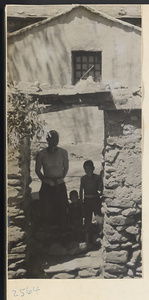Man and children in a stone gateway in front of a house on the way to the Lost Tribe country