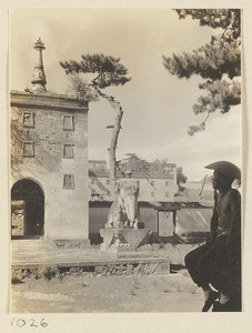 Detail of Wu ta men at Pu tuo zong cheng miao showing eastern-most arch, stone elephant, and a man sitting in the courtyard with a Bai tai in the background