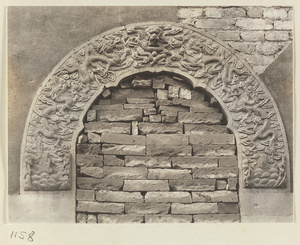 Detail of a gate at Yi li miao showing a bricked-up marble archway with a dragon motif