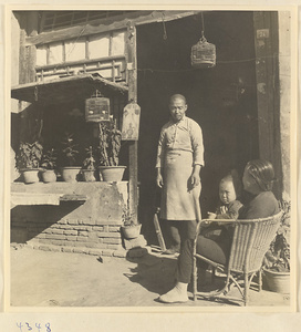 Facade of a Muslim café that sells halal food with shop sign, bird cages, man in apron, woman, and child in Baoding