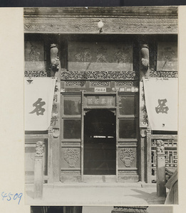 Facade detail of a shop that sells tea showing entrance, shop signs, and carved animals