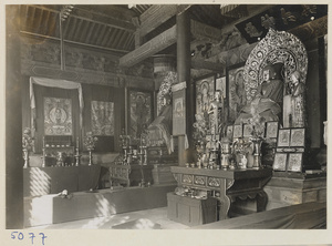 Interior of temple building at Yong he gong showing altar with Buddha statue and paintings
